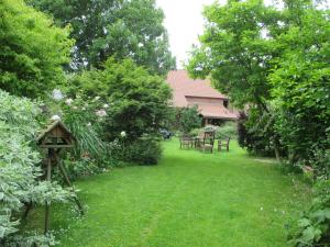 un jardin avec des chaises et une maison ornithologique dans l'herbe dans l'établissement Gîte L'air pur, à Roisin