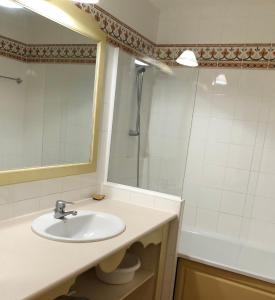 uma casa de banho com um lavatório, um espelho e uma banheira em Residence le village em Les Issambres