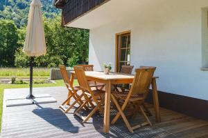 a wooden table with chairs and an umbrella on a deck at Pr' Kovač apartments in Bohinjska Bela