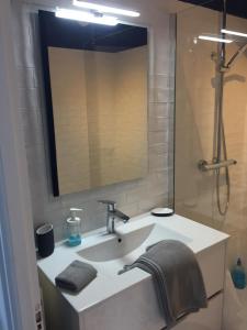 een badkamer met een wastafel met een spiegel en een douche bij Appartement Design VII Port de Tréboul-Douarnenez in Douarnenez