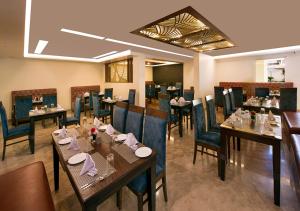 um restaurante com mesas de madeira e cadeiras azuis em Clarks Inn Suites Katra em Katra