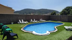 a swimming pool in a yard with chairs and a fence at Hotel Rústico Prado da Viña in Finisterre