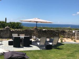 een tafel en stoelen met een parasol en de oceaan bij Le Clos de la Pointe Saint-Mathieu in Plougonvelin