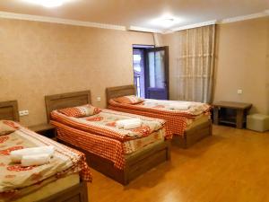 a room with three beds and a table in it at Irina's Guesthouse in Mestia