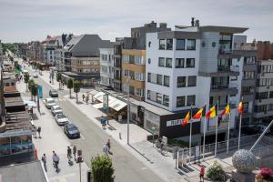 a city street with buildings and people walking and flags at Design appartement Zeelaan Koksijde in Koksijde