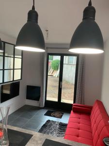 a living room with a red couch and two large lights at Manifique Maison T2 50m2 Atypique wifi & parking privée in Oullins