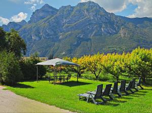 eine Reihe von Stühlen und einen Tisch mit einem Sonnenschirm in der Unterkunft Agritur Planchenstainer in Riva del Garda