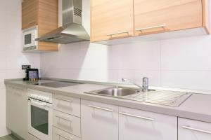 una cocina con armarios blancos y fregadero en Apartamento Málaga Litoral Beach II, en Málaga