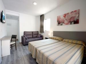 pokój hotelowy z łóżkiem i kanapą w obiekcie Hostal Anna Benidorm w mieście Benidorm
