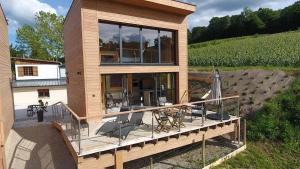 une maison avec une terrasse dotée de chaises et d'un parasol dans l'établissement COTTAGES ANTOINETTE, à Chigny-les-Roses