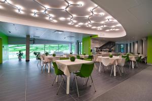 Green Hotel Płock في بلوك: مطعم بطاولات بيضاء وكراسي وجدران خضراء