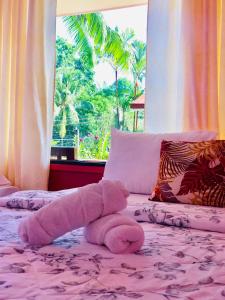 a teddy bear laying on a bed with a window at Havendwell Garden Resort in Bokbok