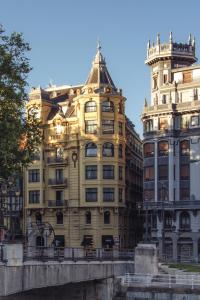 ein großes gelbes Gebäude neben einem hohen Gebäude in der Unterkunft Hotel Tayko Bilbao in Bilbao