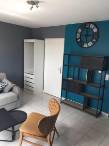 uma sala de estar com um relógio numa parede azul em Résidence Studio Grand Luxe Wifi parking privé em Vaulx-en-Velin