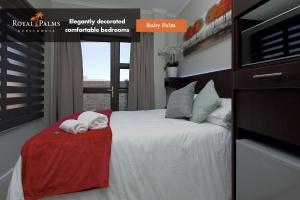 1 dormitorio con 1 cama y toallas en una mesa en Royal Palms Guest House, en Port Elizabeth