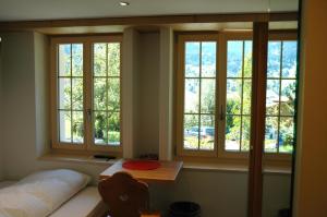 Zimmer mit 3 Fenstern, einem Bett und einem Tisch in der Unterkunft Ferienwohnung Uf dr Liwwi in Grindelwald