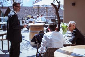Ein Mann im Anzug unterhält sich mit zwei Männern, die an Tischen sitzen. in der Unterkunft Hotel Weinstube in Nendeln