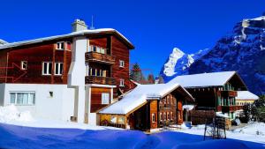 a building in the snow with a mountain in the background at Chalet Anemone 2 in Mürren