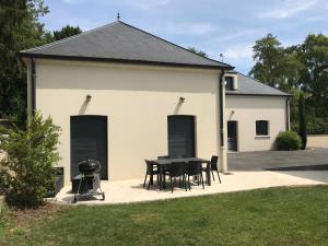 a building with a table and chairs and a grill at Champagne BNB - La Source in Fontaine-sur-Ay