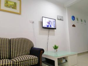 a living room with a couch and a table and a tv at NAZ Homestay in Jitra