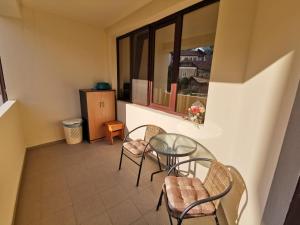 a balcony with a table and chairs and a window at Apartament Catia in Călimăneşti +1 photo