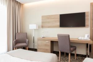 a hotel room with a desk with a television on the wall at Z-Hotel Business & Spa in Otwock