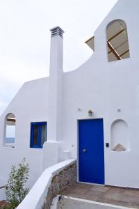 niebieskie drzwi na boku białego budynku w obiekcie Muses seaside Villas w mieście Paralio Astros