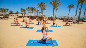 een groep mensen die yoga doen op het strand bij Blend Elphistone Resort Marsa Alam in Abu Dabab