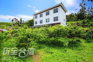 a white house sitting on top of a lush green field at Do Tian Ding B&B in Lugu