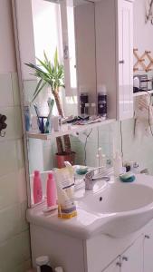 een badkamer met een witte wastafel en een spiegel bij CozyandCalm in Florence