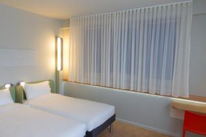 a bedroom with a white bed and white curtains at Ibis Budget Braga Centro in Braga