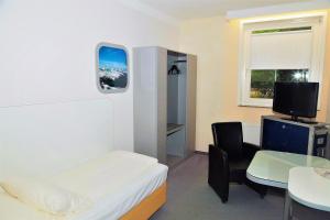 a room with a bed and a table and a tv at Hotel Cockpit in Hamburg