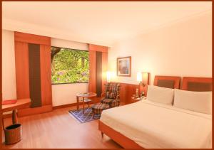 a hotel room with a bed and a chair and a window at Trident Chennai in Chennai