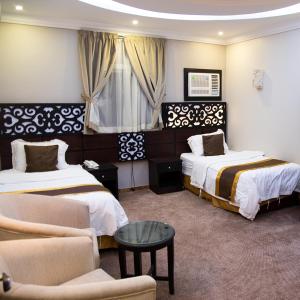 a hotel room with two beds and a couch at City Center Plaza Aparthotel in Jeddah