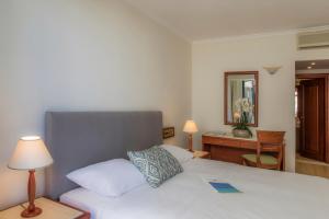 a bedroom with a bed and a desk with a mirror at Mitsis La Vita in Rhodes Town