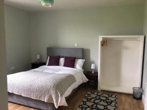 - une chambre avec un grand lit blanc et des oreillers violets dans l'établissement Shannon's House, à Doolin