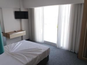 Amphora Hotel في أيفاليك: غرفة نوم بسرير ونافذة كبيرة