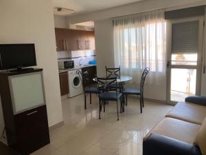 a living room with a table and chairs and a kitchen at APARTAMENTOS ESJOVIAL in Los Alcázares