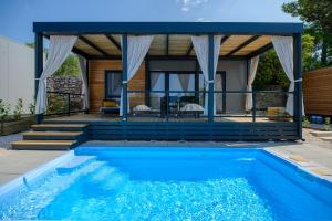 a villa with a swimming pool in front of a house at Medora Orbis Mobile Homes & Glamping in Podgora