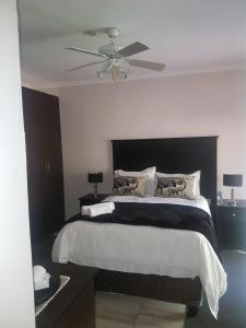 a bedroom with a large bed with a ceiling fan at Sekelbos Guesthouse in Pretoria