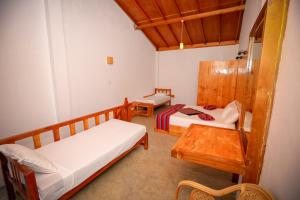 um pequeno quarto com duas camas e uma mesa em The Tea Tree Resort em Bandarawela