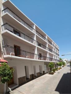 a white apartment building with balconies on a street at Hostal Sa Rota in Santa Eularia des Riu