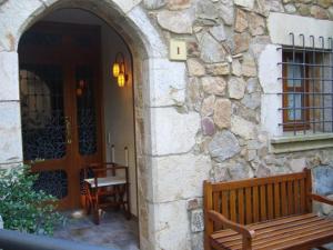 eine Holzbank neben einem Steingebäude mit einer Tür in der Unterkunft Beautiful apartment in Tossa de Mar in Tossa de Mar