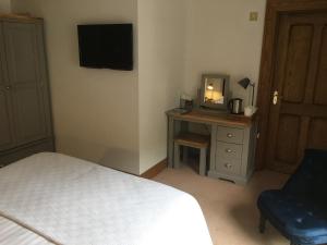 a bedroom with a bed and a desk with a television at Dale Head Hall Lakeside Hotel in Keswick