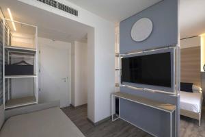 a living room with a large tv and a bedroom at Hotel Baia in Rimini