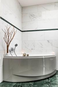 y baño con bañera blanca y azulejos blancos. en Dreamapartment La Vigna Suite mit eigenem Indoorpool & Sauna - Weil am Rhein en Weil am Rhein