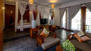 a hotel room with a bed and a living room at La Rivière d' Angkor Resort in Siem Reap