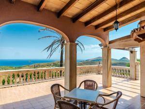 eine Terrasse mit einem Tisch, Stühlen und Meerblick in der Unterkunft Villa Cala Torta Na Lluny by Interhome in Cala Mesquida