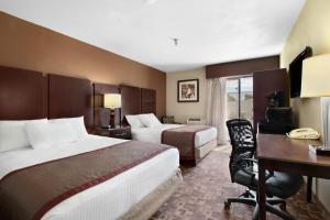 a hotel room with two beds and a desk at Rodeway Inn & Suites Chandler - Phoenix South I-10 in Chandler