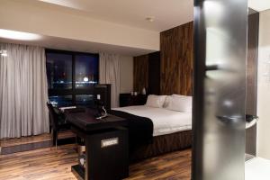a hotel room with a bed, desk and a television at Colosseum Luxury Hotel in Cape Town